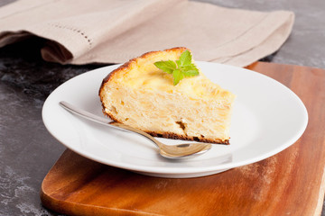 piece of cottage cheese pie with mint on a plate, closeup