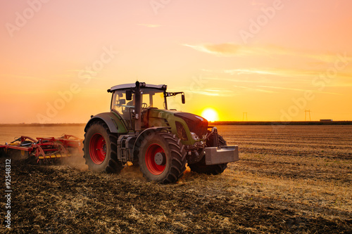 Fotografía Tractor en el campo de la cebada por la puesta del sol.