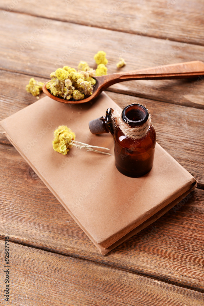 Old book with dry flowers and bottle on table close up