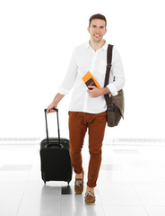 Wall Mural - Man holding suitcase on light background