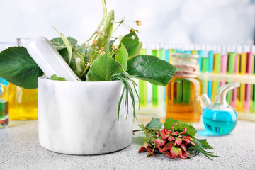 Wall Mural - Herbs in mortar, test tubes and pills,  on table, on light background