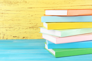 Poster - Colorful books on yellow wooden background