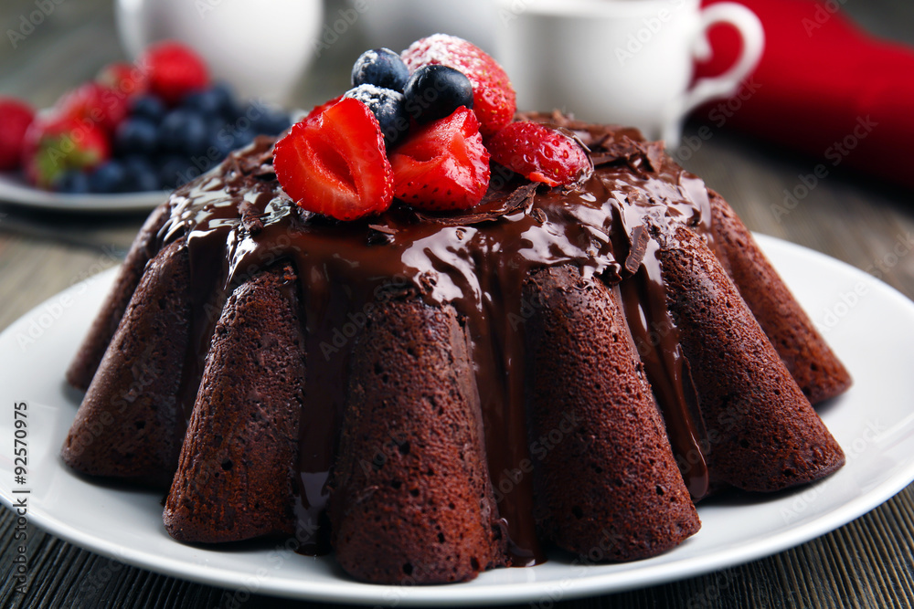 Delicious chocolate cake with berries in plate on table, closeup