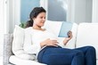© WavebreakmediaMicro - Happy woman reclining on sofa with tablet