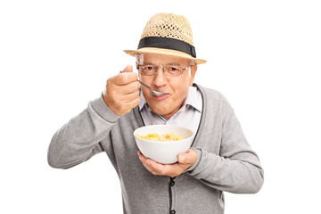 Wall Mural - Senior man eating cereal with a spoon