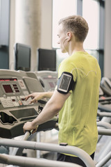 Wall Mural - man with smartphone exercising on treadmill in gym