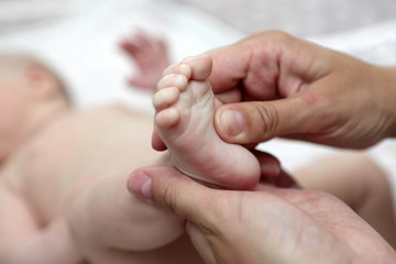 mother massaging the newborn baby foot