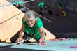 © alexbrylovhk - Aged Woman Climbing WallElderly Female Demonstrates Excellent Physical and Moral Abilities Ascending Vertical Climbing Wall Group of Climbers Staying Below on Ground