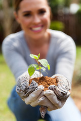 woman holding soil and a plant