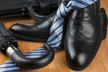 Classic men's shoes, tie, umbrella and bag on the wooden floor