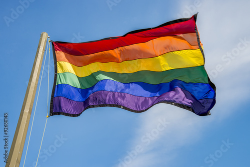 Pinturas sobre lienzo Gay rainbow flag waving over blue sky background
