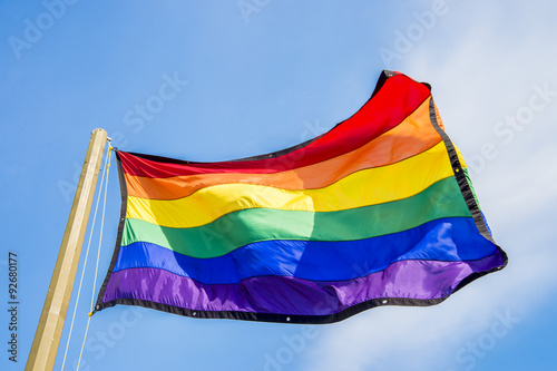 Pinturas sobre lienzo Gay rainbow flag waving over blue sky background