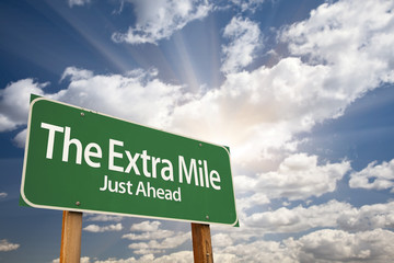 Canvas Print - The Extra Mile Green Road Sign Over Clouds