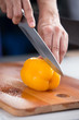 © coolmodeling - yellow bell pepper on a wooden cutting board being cut in half by a knife