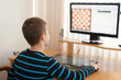 Little boy play online chess at home