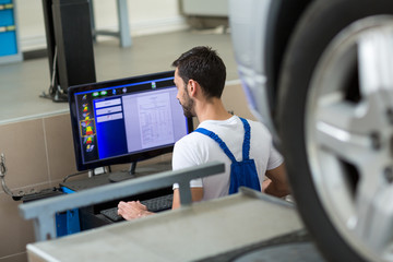 Mechanic working on car by computer