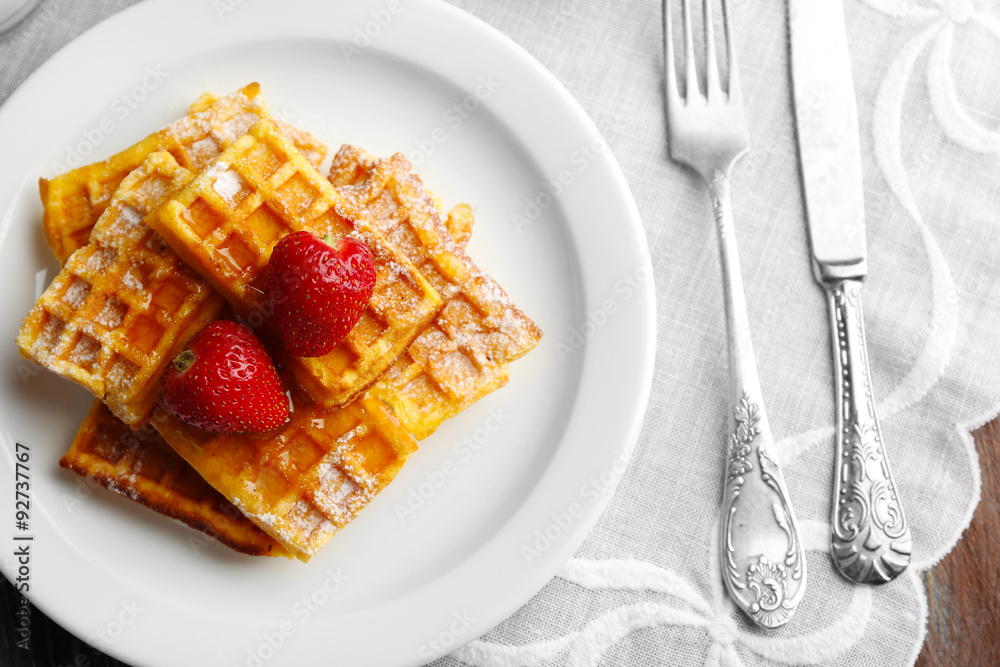 Sweet homemade waffles with strawberries  on plate, on table background