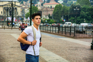 Wall Mural - Handsome young man walking in European city square