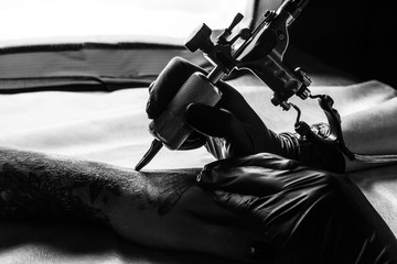 Tattooist makes tattoo on clients arm in bw