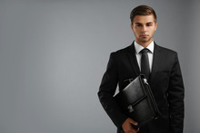 Elegant Man In Suit With Briefcase On Gray Background