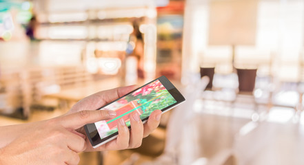 Wall Mural - male hand is holding a modern touch screen phone and Coffee shop