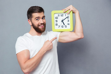 Poster - Smiling man pointing finger on wall clock