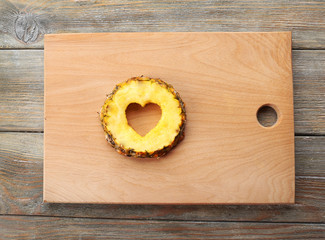 Poster - Pineapple slice with cut in shape of heart on wooden background