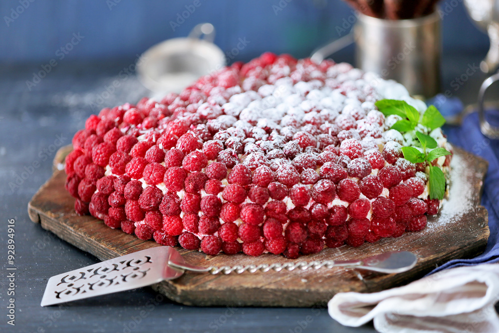 Sweet cake with raspberries on color wooden background