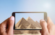 Male hand taking photo of Great pyramids in Giza with cell, mobile phone. Egypt holiday.