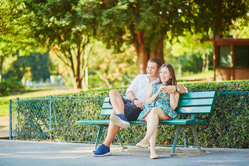 Wall Mural - Happy dating couple on a bench in a Parisian park