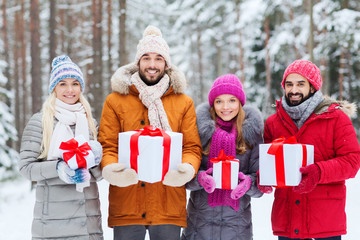 happy friends with gift boxes in winter forest