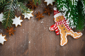 Wall Mural - wooden background with fir branches, cookies and gingerbread man