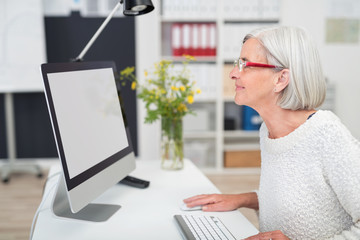 Canvas Print - ältere frau im büro schaut auf computer