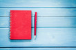 © pingpao - Red notebook with pen on blue wooden table