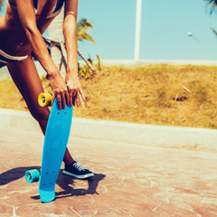 sexy suntanned lady staying with blue penny board on the streat