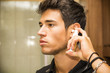 © theartofphoto - Young Man Spraying Ear Spray into Ears