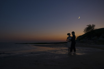 Silhouette of a girl and guy night on the coast