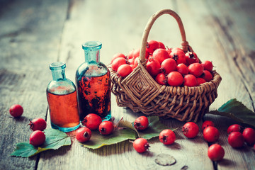 Wall Mural - tincture bottles of hawthorn berries and ripe thorn apples in ba