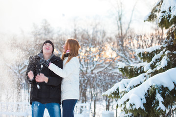 young pair walks in wood, guy and the girl play with snow near