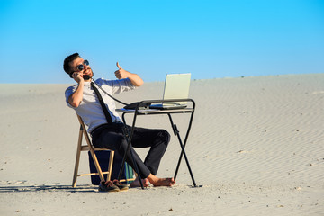 Businessman using  laptop in a desert