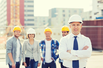 Canvas Print - group of smiling builders in hardhats outdoors