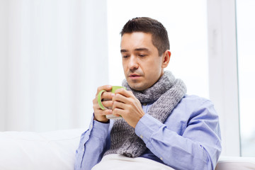 Wall Mural - ill man with flu drinking hot tea from cup at home