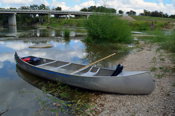 Canoe Beach/Two person canoe sitting on the bank of a river.