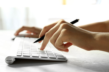 Sticker - Female hand with pen typing on keyboard at table, closeup