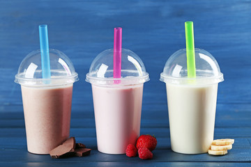Wall Mural - Plastic cups of milkshake on color wooden background