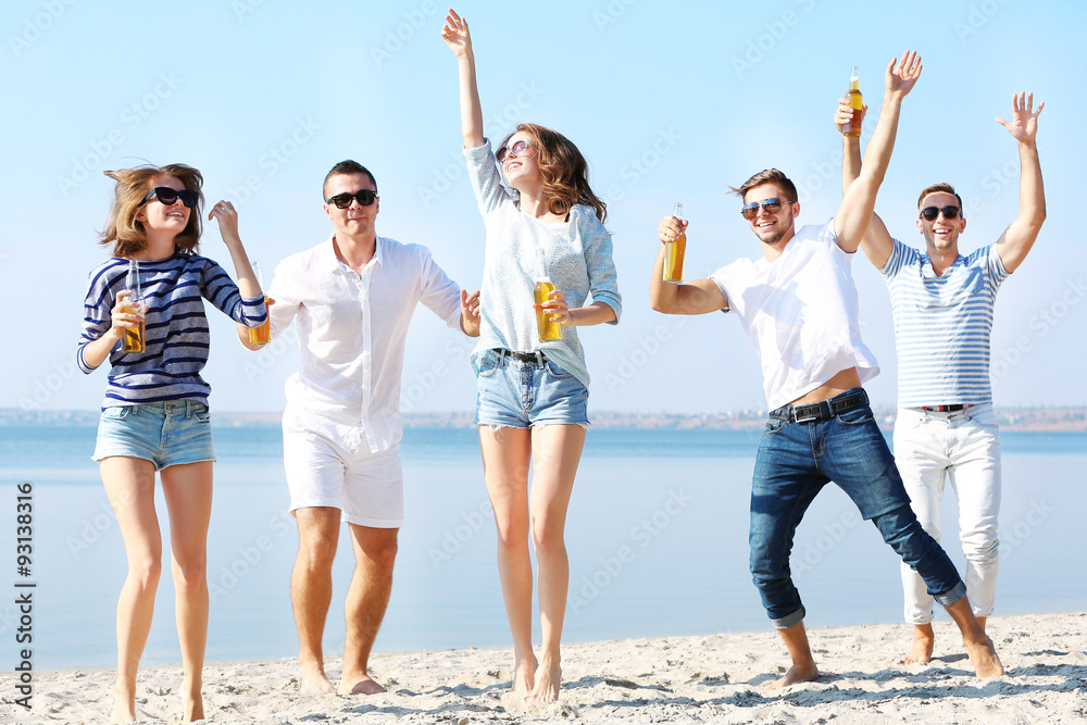 Young people with beer on the riverside