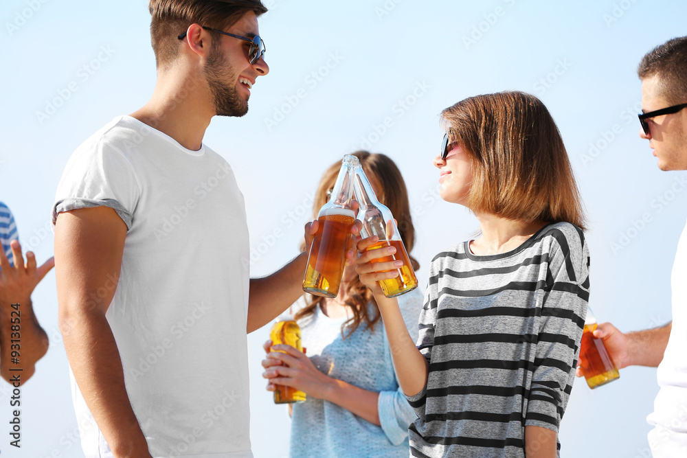 Young people with beer on the riverside