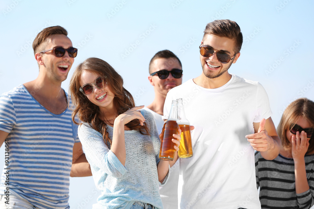 Young people with beer on the riverside
