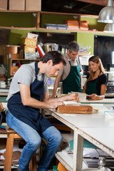 Wall Mural - Man Using Holing Machine While Colleagues Standing In Background