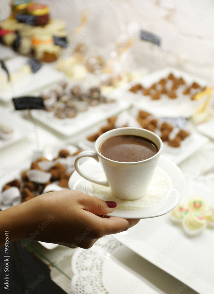 Female hand holding cup of hot chocolate on table background